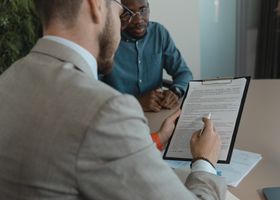 Home A recruiter reviews a candidate's documents during a job interview in a modern office setting.